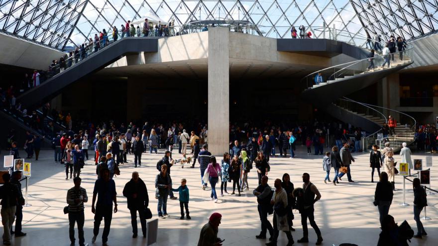 Des touristes sous la pyramide du Louvre - Paris (France)