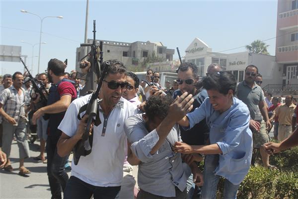 Un homme, suspecté d'avoir pris part à l'attaque, est escorté par la police tunisienne alors qu'une femme tente de le frapper (Reuters).